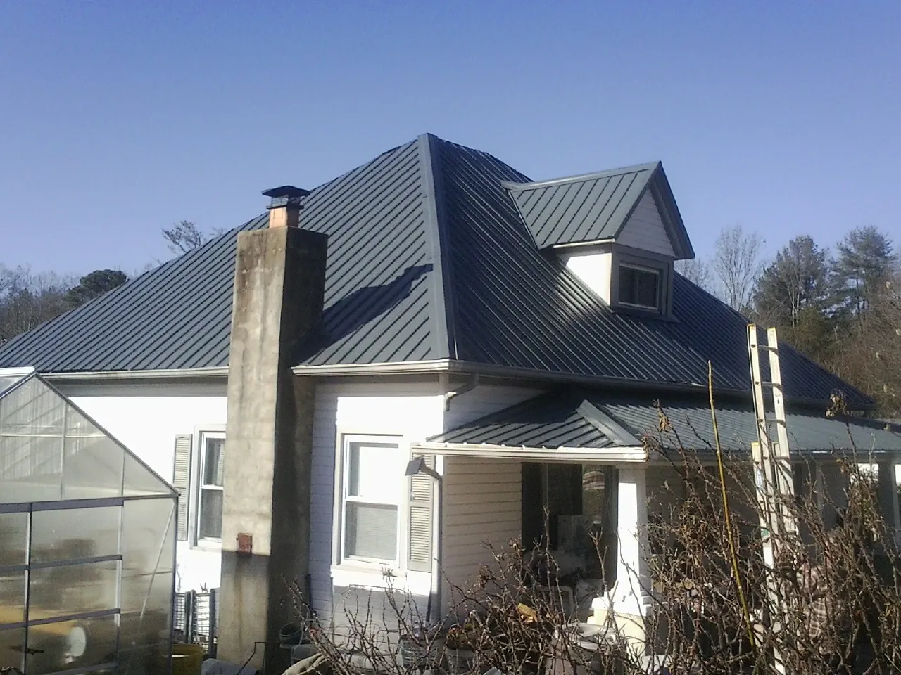 Dark blue standing seam metal roof on a white farmhouse with dormer — Slate & Tile Roof Repair by Roofing Brothers in Shelburne Falls