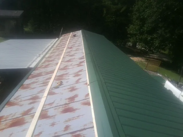Old rusted panels beside newly installed green metal roofing — Wind Damage Roof Repair by Roofing Brothers in Shelburne Falls