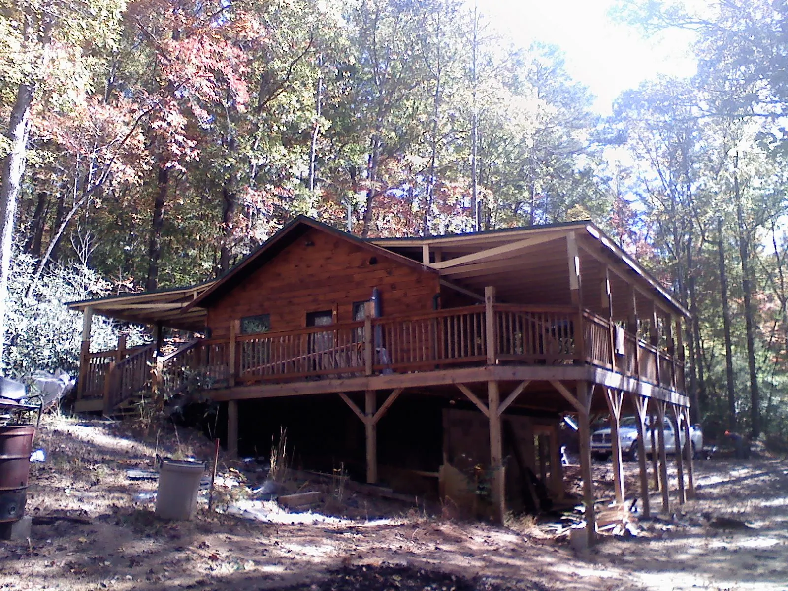 Log cabin with a wraparound porch and metal roof in the fall in Shelburne Falls