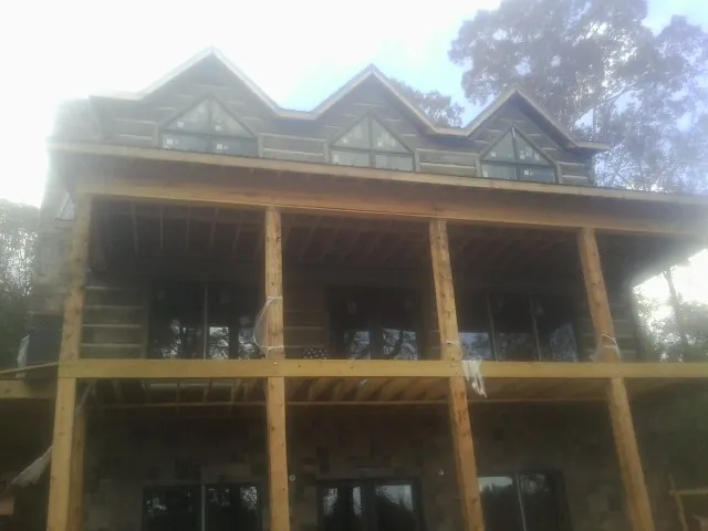 Dormers and porch framing on a large log home under construction — Roof Coating work by our crew in Shelburne Falls