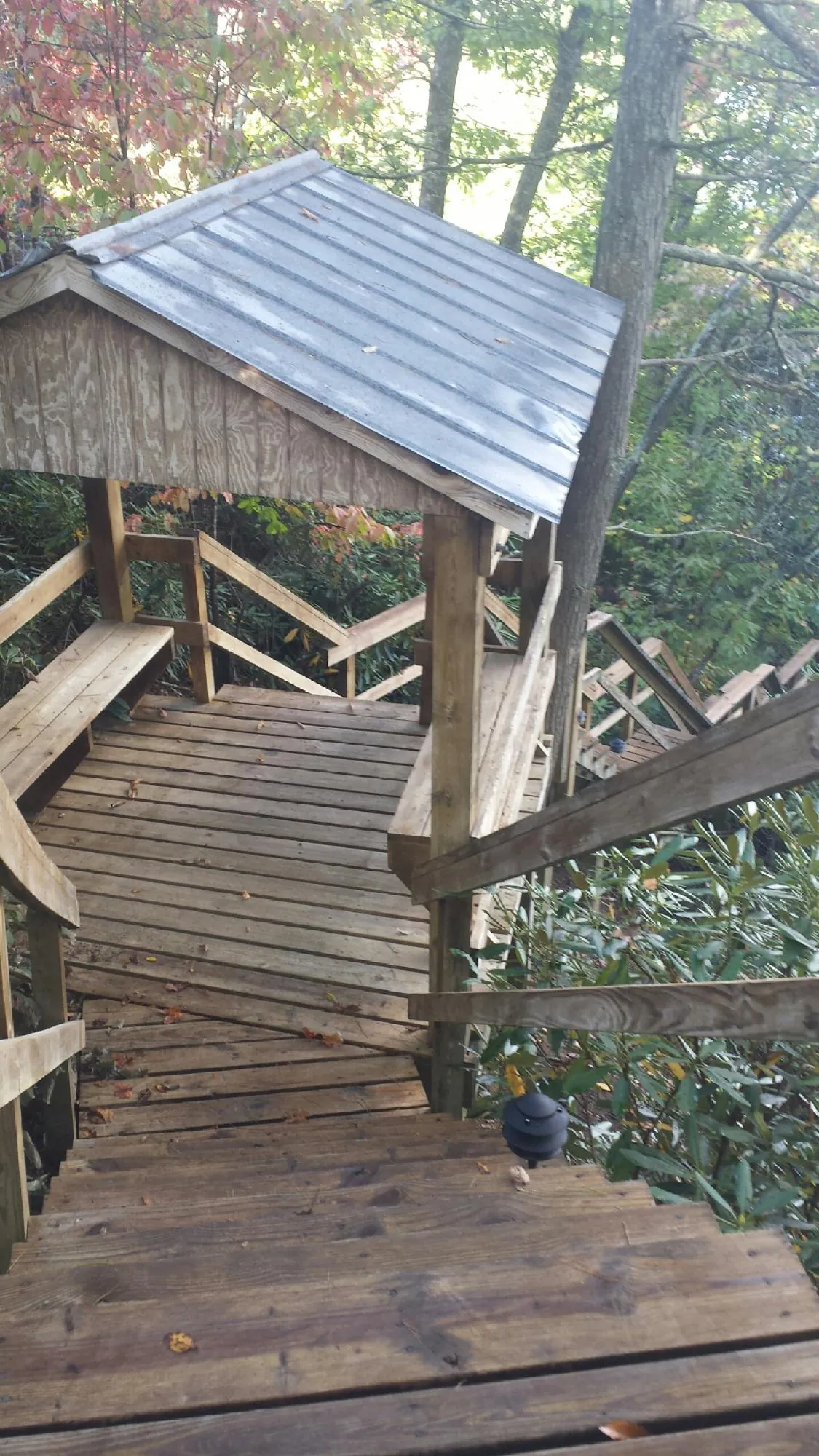 Metal roofed shelter over wooden steps on a wooded walkway — Skylight Repair & Installation work by our crew in Shelburne Falls